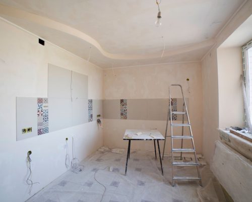 Spacious kitchen under renovation with ladder and tools, showcasing a fresh new design.